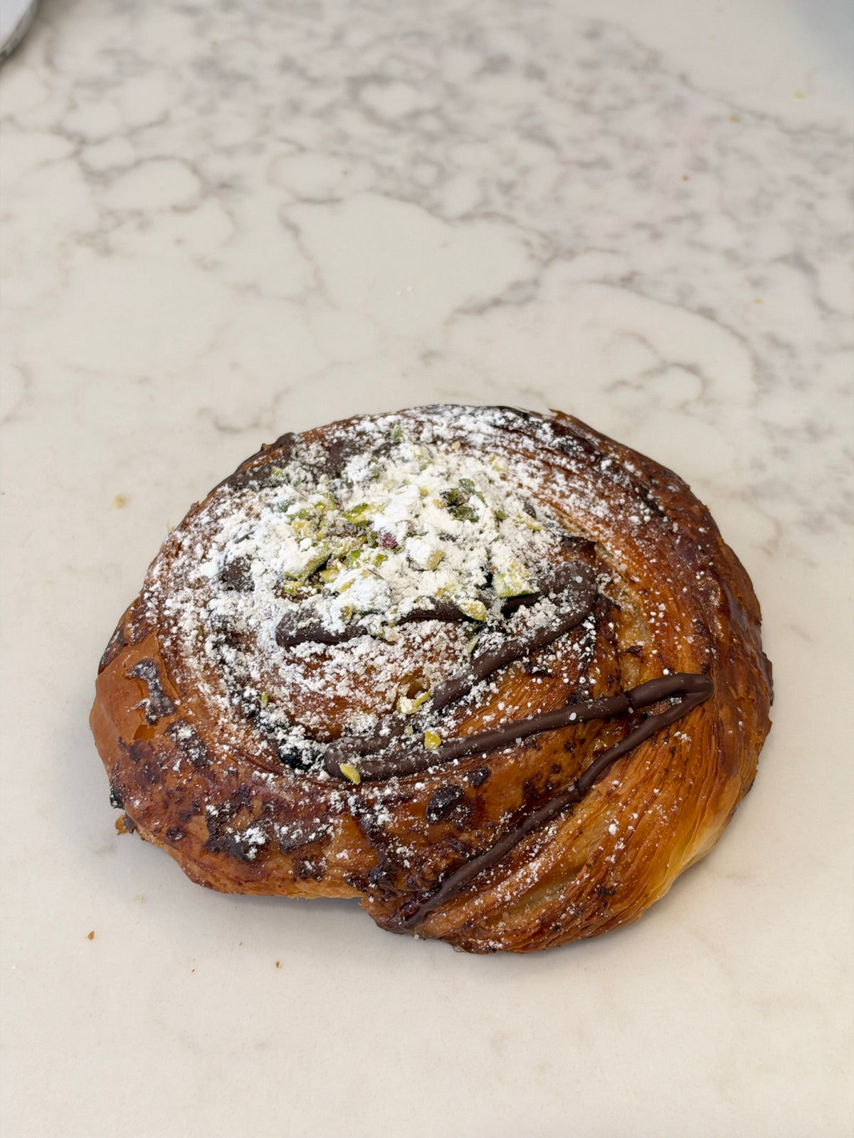 A Le 76 chocolate and pistachio snail, dusted with icing sugar