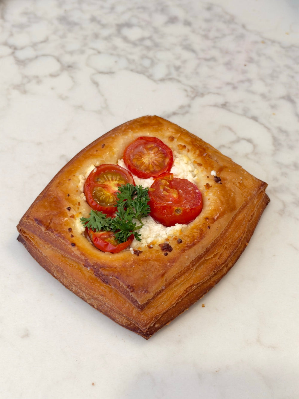 A Le 76 goat cheese and tomato danish, topped with cherry tomatoes and herbs
