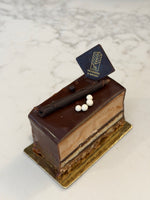 A slice of Le 76 hazelnut cake, layered praline under a chocolate glaze