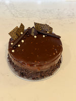 A whole Le 76 hazelnut cake, glazed and edged with chopped hazelnuts