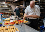 Jean-Marc Masset piping creme patissiere into tart shells in the Le 76 kitchen, strawberry tarts and eclair shells lined up on the bench