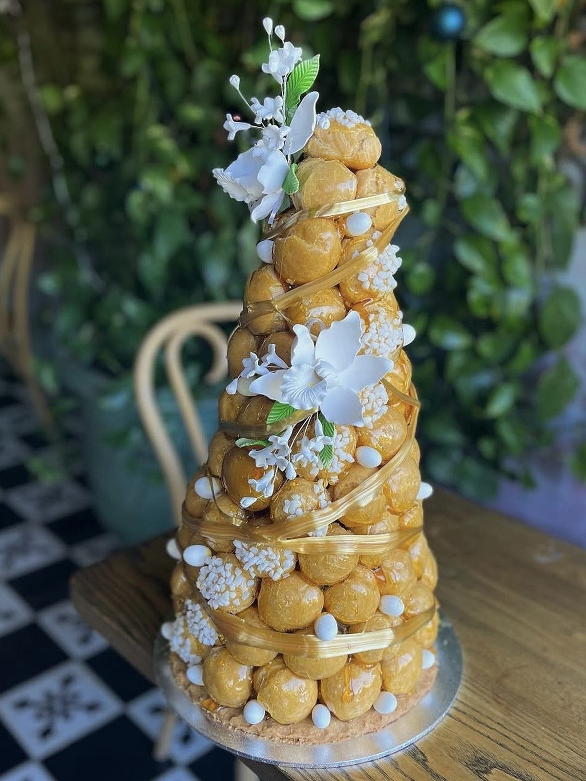 A Le 76 croquembouche, caramel glazed choux dressed with white blossom, in the shop at Neutral Bay