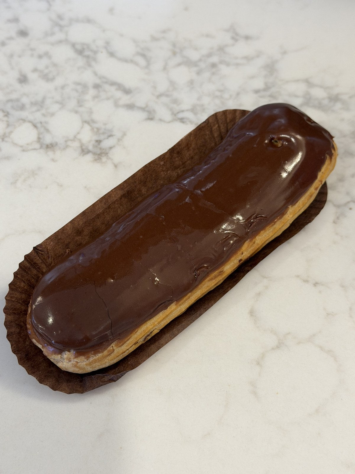 A Le 76 chocolate eclair, choux pastry filled by hand and glazed in dark chocolate