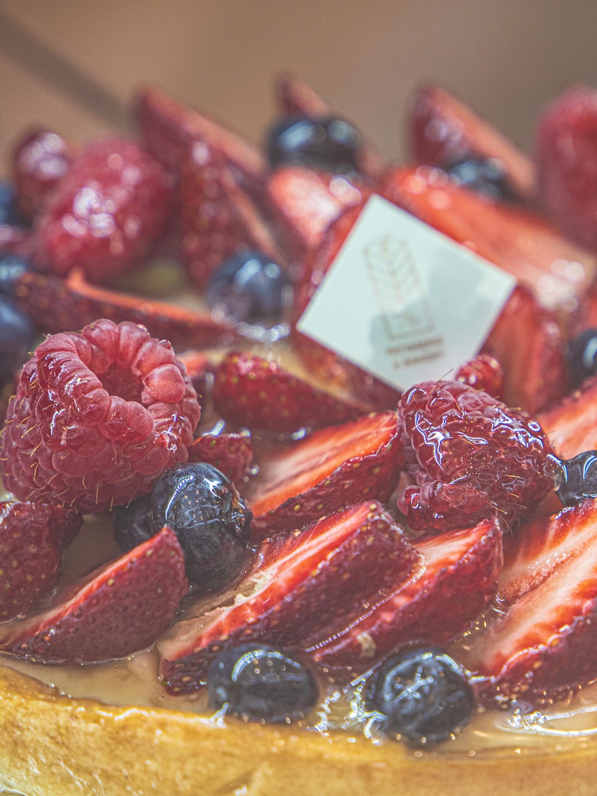 A whole Le 76 fresh fruit tart, strawberries, raspberries and blueberries on creme patissiere