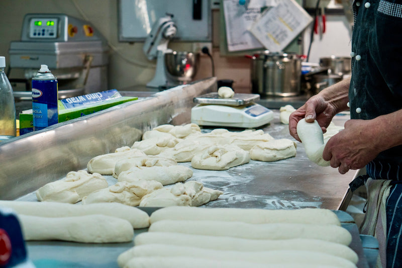 Hands shaping dough on a floured bench in the Le 76 bakehouse