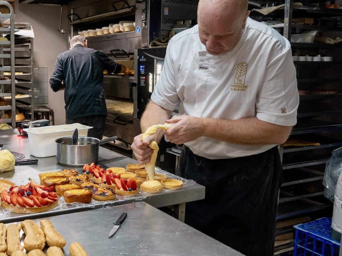Jean-Marc Masset piping filling into pastries at the bench in the Le 76 kitchen