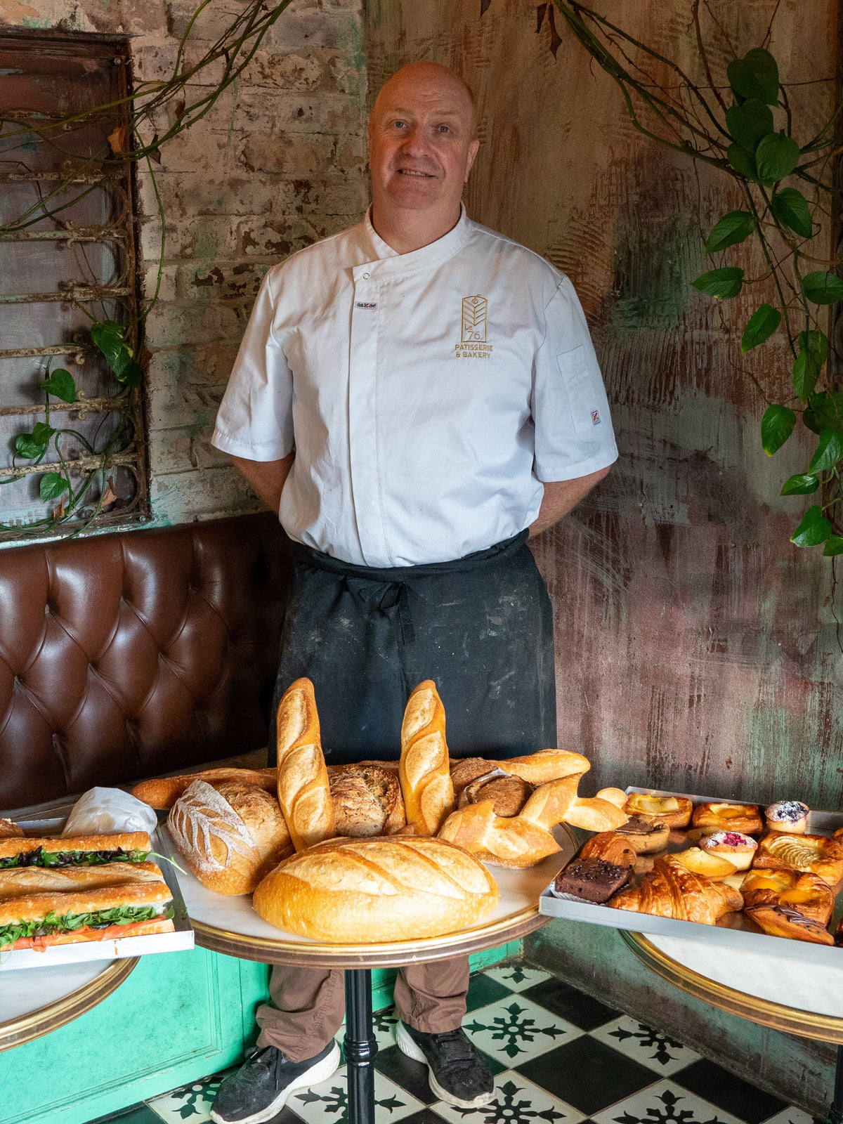 Jean-Marc Masset in his chef's whites in the shop, behind a counter of baguettes and pastries