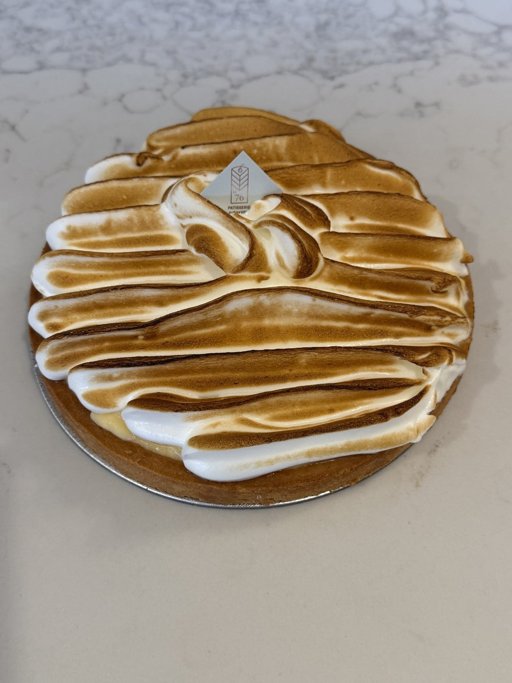 A whole Le 76 lemon meringue tart, meringue piped in sweeps and torched by hand