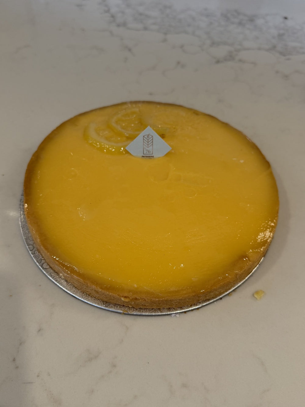 A whole Le 76 lemon tart, smooth lemon curd set in thin sweet pastry