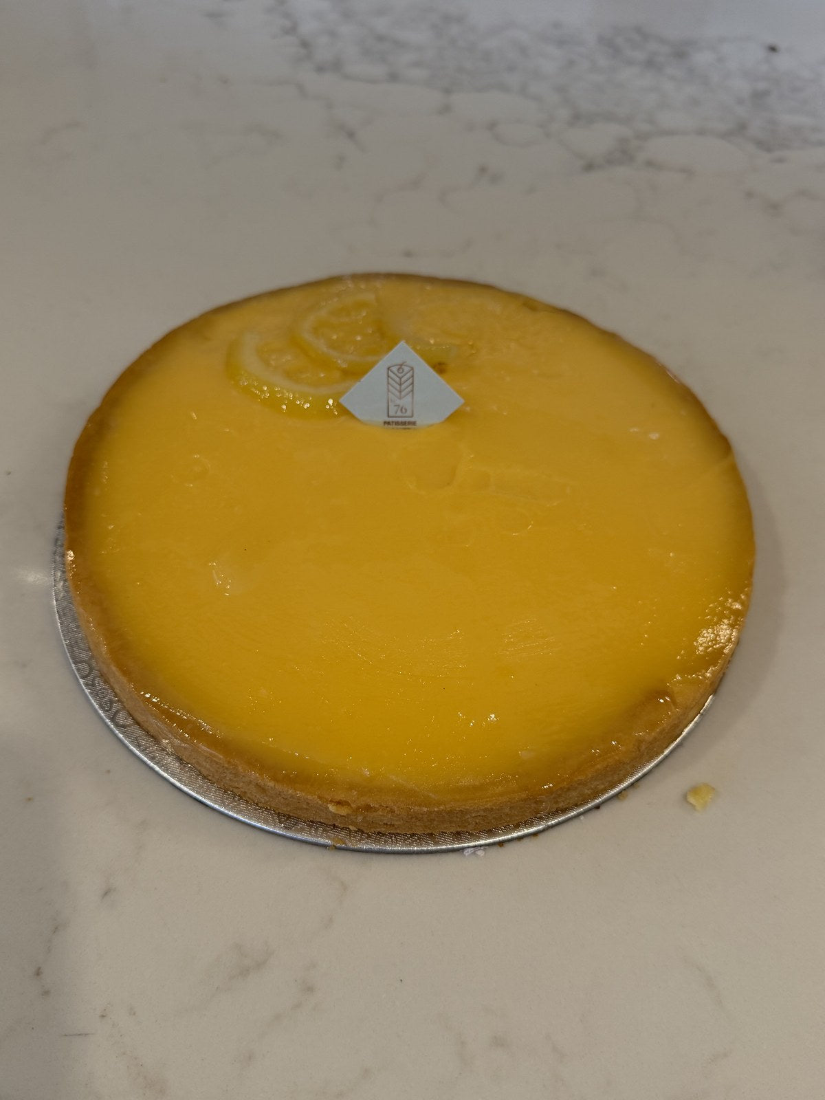 A whole Le 76 lemon tart, smooth lemon curd set in thin sweet pastry