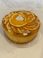 A whole Le 76 orange and almond cake, gluten and dairy free, topped with orange slices