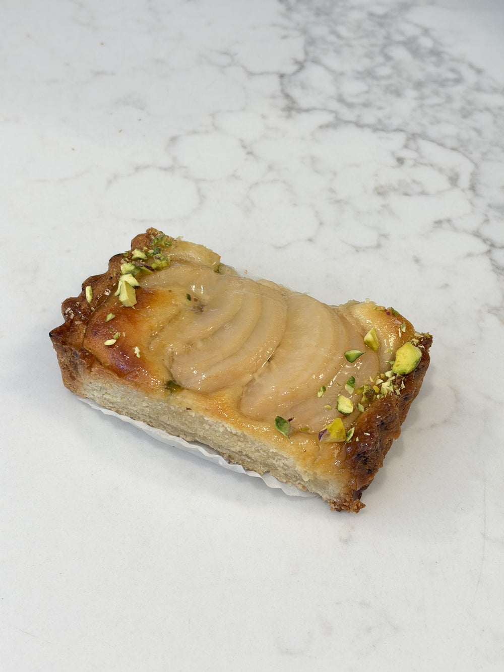 A Le 76 pear and pistachio slice, poached pear on frangipane with chopped pistachio