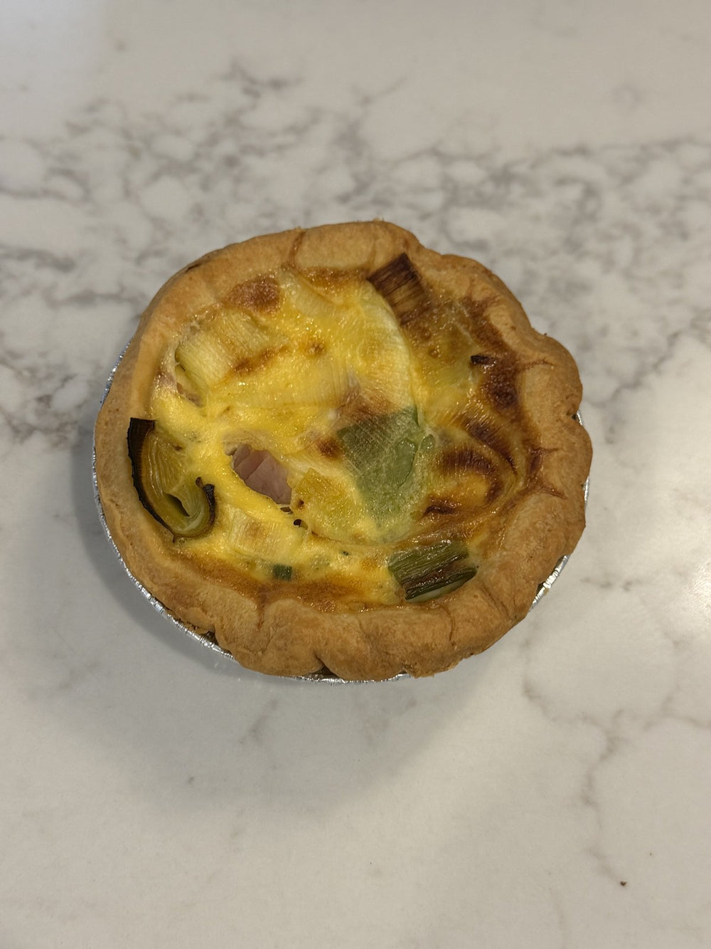 An individual Le 76 quiche, savoury custard baked in shortcrust pastry