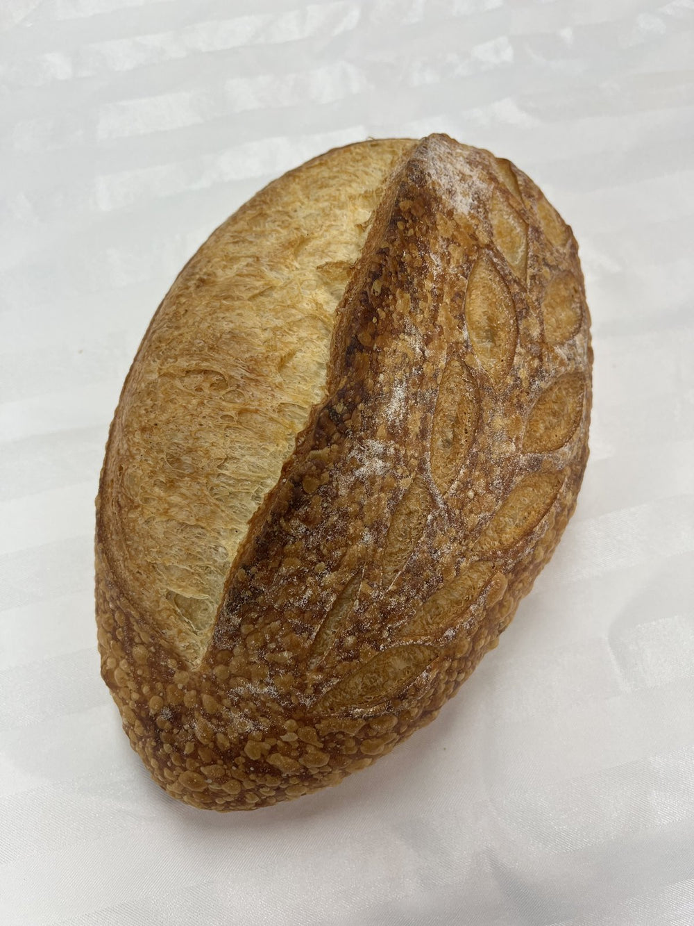 A Le 76 sourdough loaf, oval with a single deep slash across the top