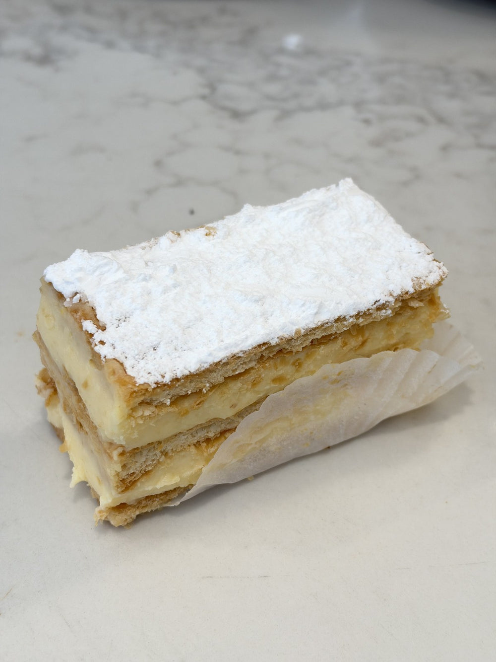 A Le 76 vanilla slice, custard set between two sheets of puff pastry and dusted with icing sugar