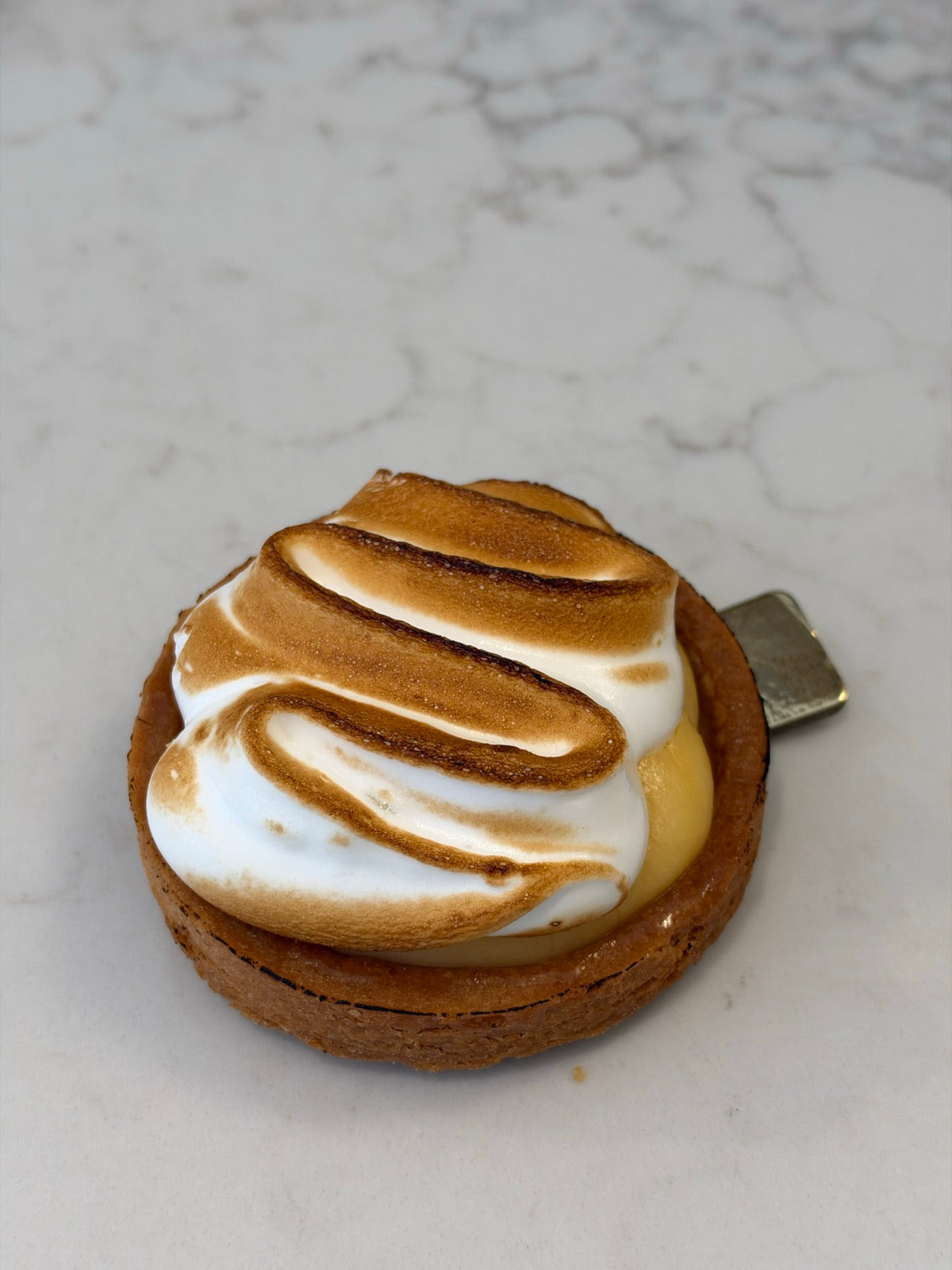 An individual Le 76 lemon meringue tart with torched meringue