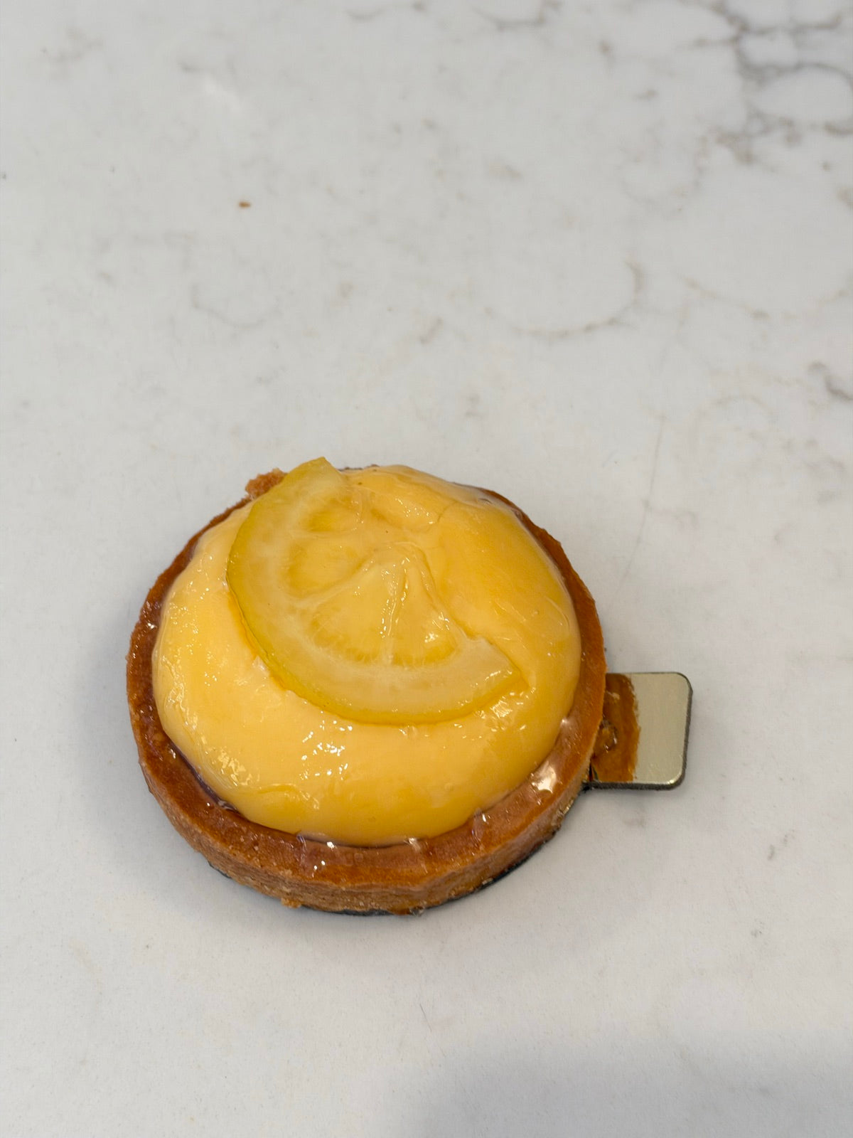 An individual Le 76 lemon tart with a smooth lemon curd top