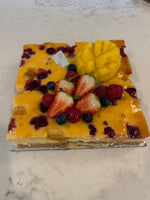A whole Le 76 baked cheesecake topped with mango, strawberries and berries
