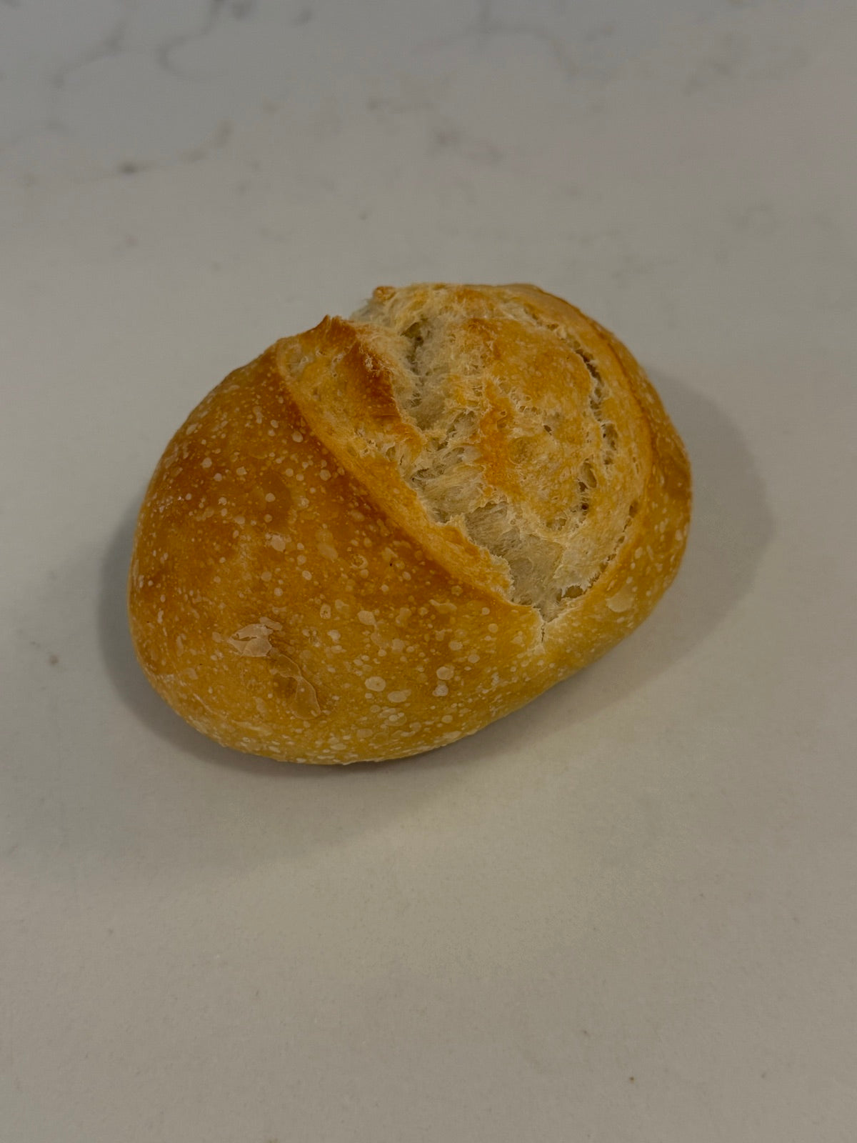 A Le 76 sourdough roll, scored once across the top